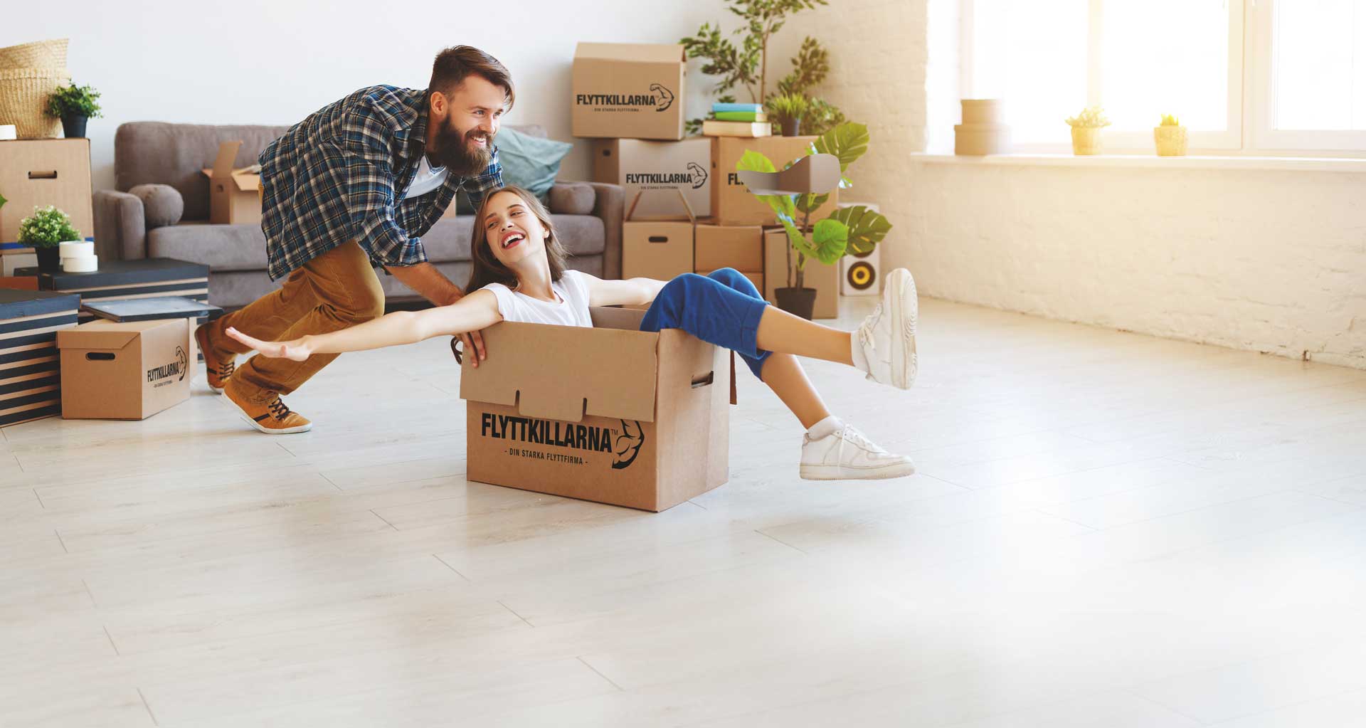 Smiling couple enjoying their new home with Flyttkillarna moving boxes